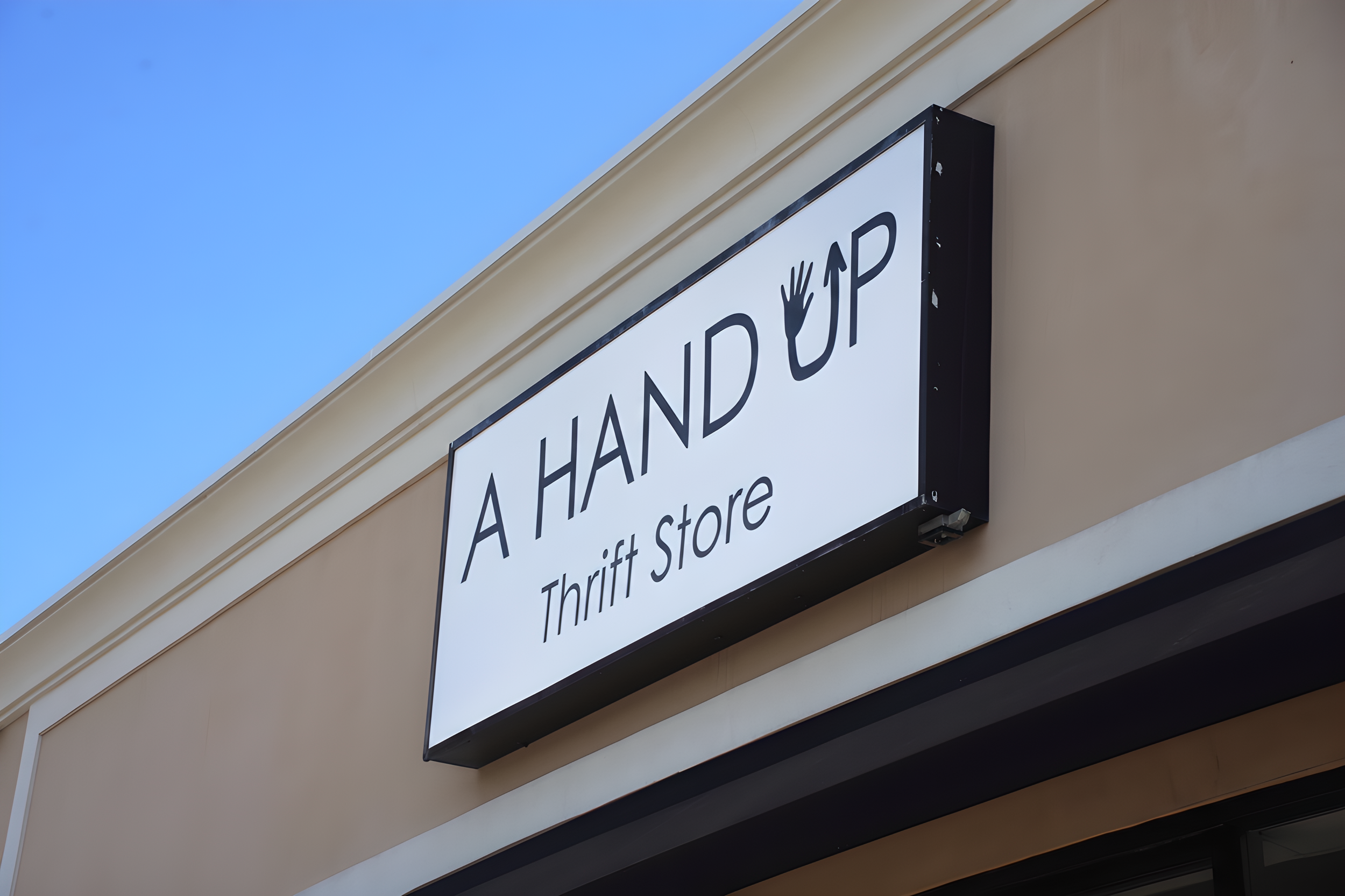 The A Hand Up Thrift Store sign mounted on the storefront